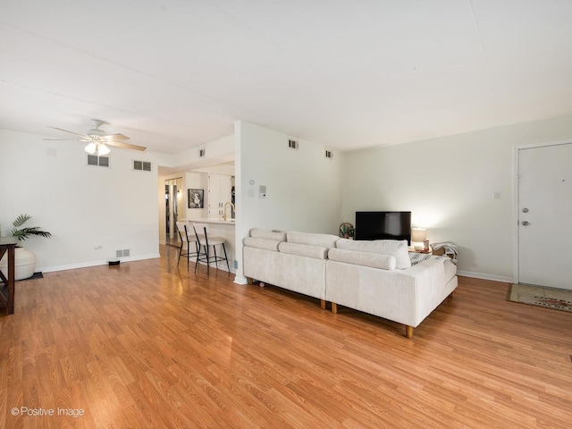 living area with light wood-type flooring, a ceiling fan, and visible vents