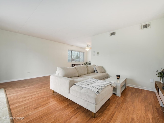 living area featuring ceiling fan, baseboards, visible vents, and light wood-type flooring