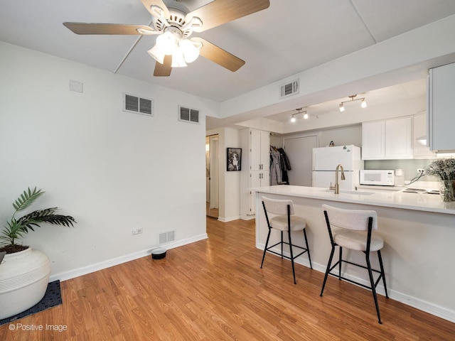 kitchen featuring a peninsula, white appliances, and visible vents