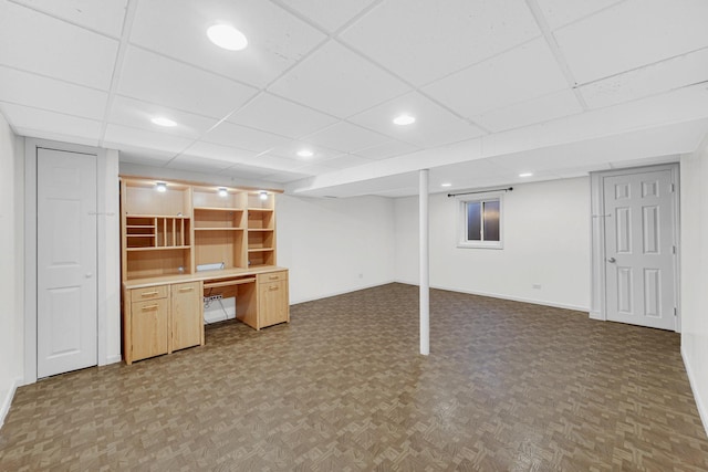 finished basement featuring recessed lighting, a paneled ceiling, baseboards, and parquet floors