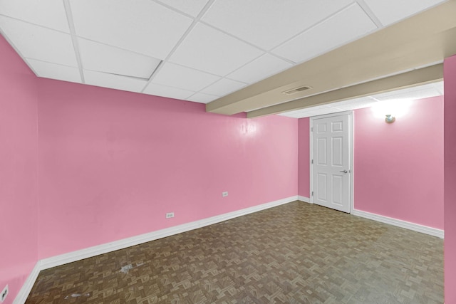 finished basement with parquet floors, baseboards, a drop ceiling, and visible vents
