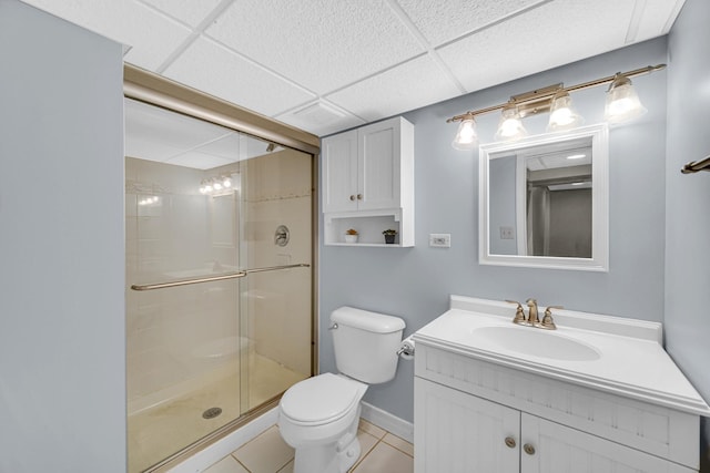 bathroom featuring toilet, tile patterned flooring, a shower stall, and a drop ceiling