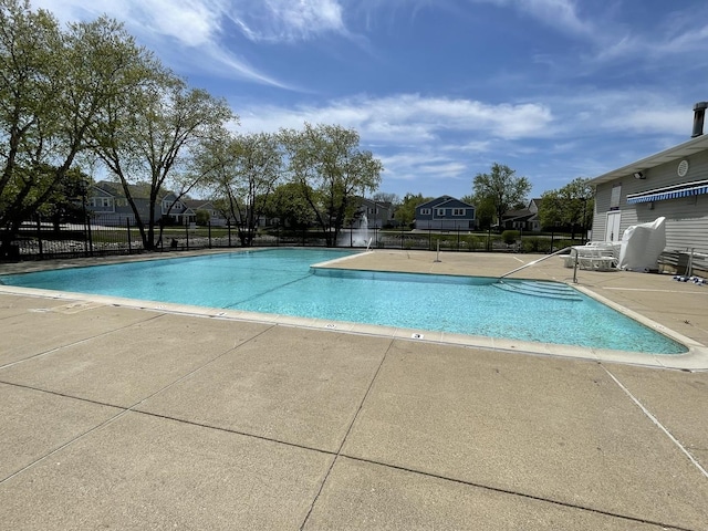community pool featuring fence, a patio area, and a residential view