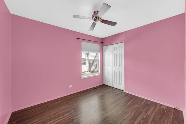 unfurnished bedroom featuring wood finished floors, a closet, baseboards, and ceiling fan