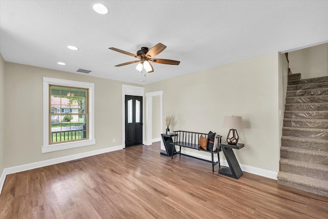 entryway featuring ceiling fan, visible vents, wood finished floors, and stairway