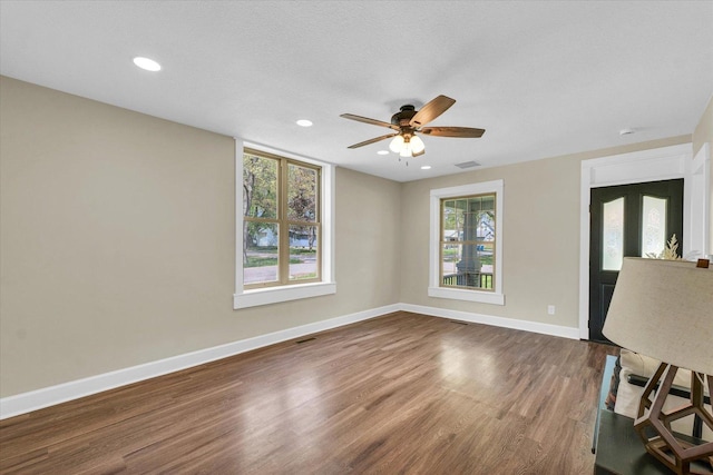 interior space featuring a ceiling fan, visible vents, baseboards, recessed lighting, and dark wood-type flooring