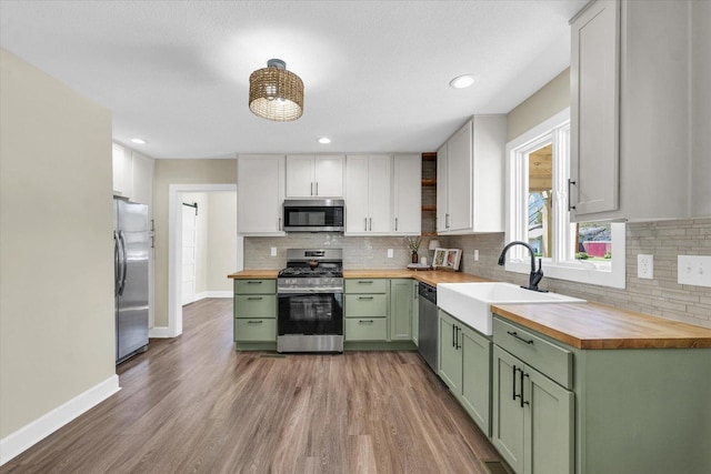 kitchen with wooden counters, appliances with stainless steel finishes, and green cabinets