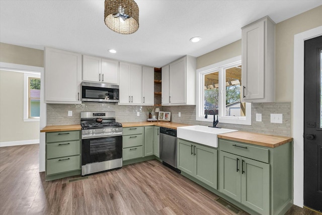 kitchen featuring appliances with stainless steel finishes, green cabinets, and wooden counters