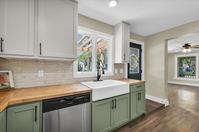 kitchen with green cabinetry, a sink, dishwasher, tasteful backsplash, and butcher block counters