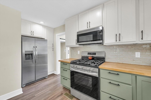 kitchen with green cabinetry, appliances with stainless steel finishes, wooden counters, light wood-style flooring, and baseboards