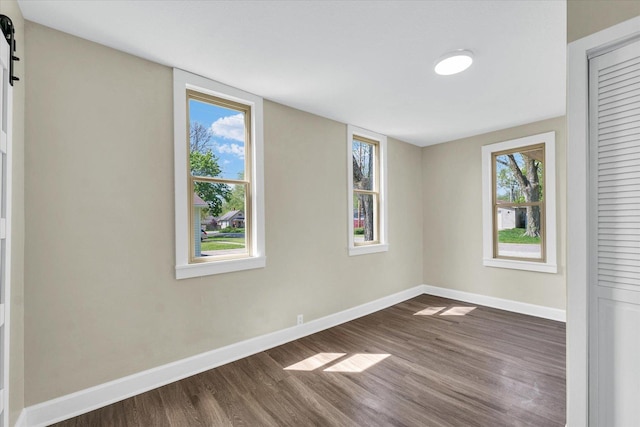spare room with a healthy amount of sunlight, baseboards, and dark wood-style flooring