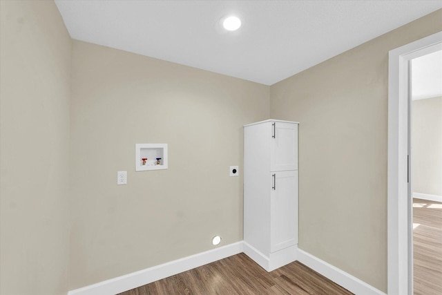 washroom featuring hookup for an electric dryer, cabinet space, wood finished floors, baseboards, and hookup for a washing machine