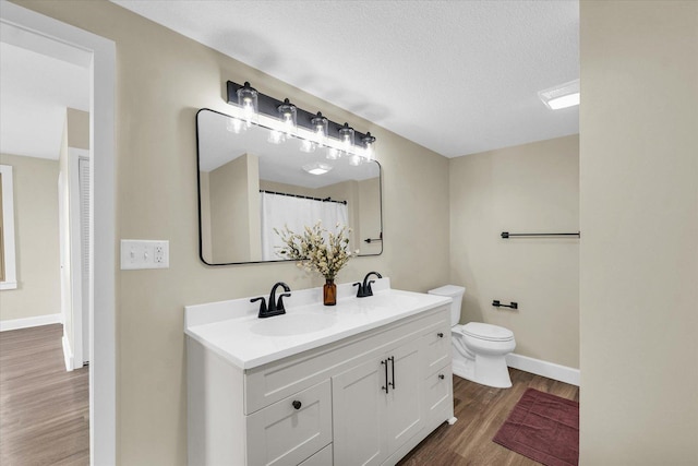 full bathroom with toilet, baseboards, a sink, and wood finished floors