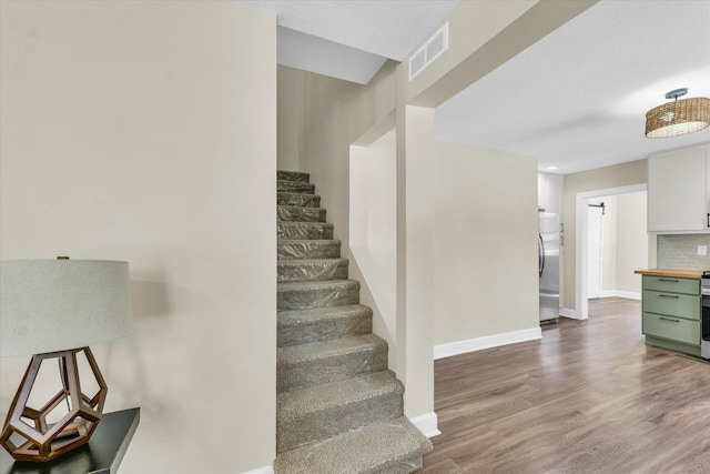 stairs with baseboards, visible vents, and wood finished floors