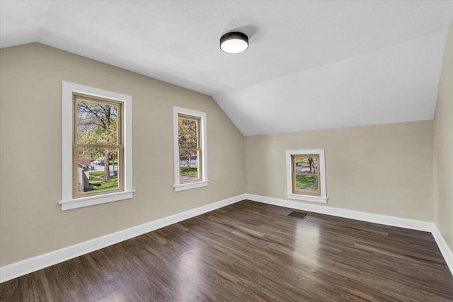 bonus room featuring baseboards, vaulted ceiling, and dark wood finished floors