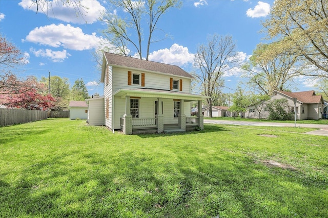 traditional-style house with a porch, fence, and a front yard