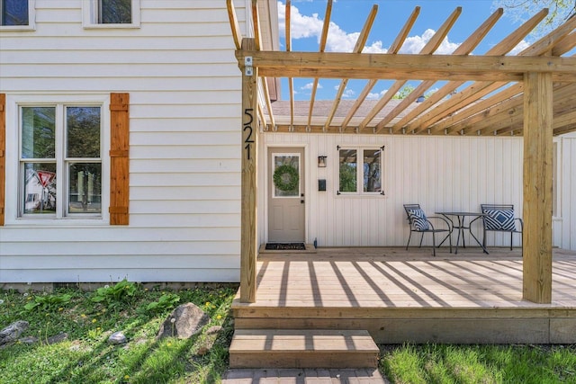 view of exterior entry featuring a pergola and a wooden deck