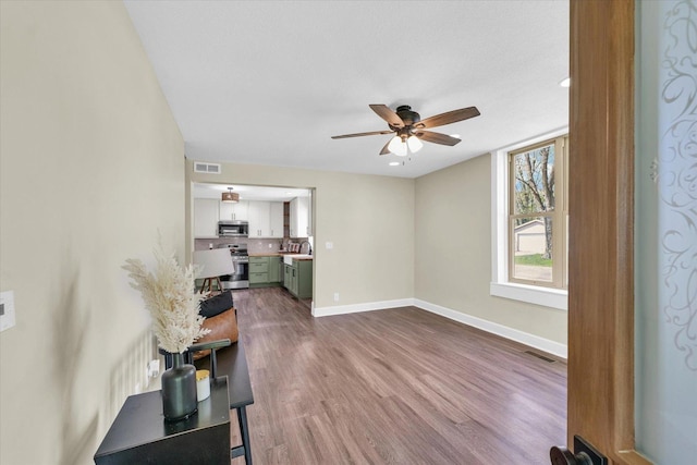 living area featuring visible vents, a ceiling fan, baseboards, and dark wood-type flooring