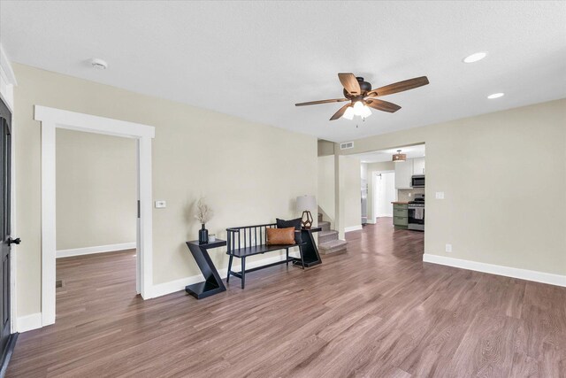 living area featuring a ceiling fan, baseboards, visible vents, and wood finished floors