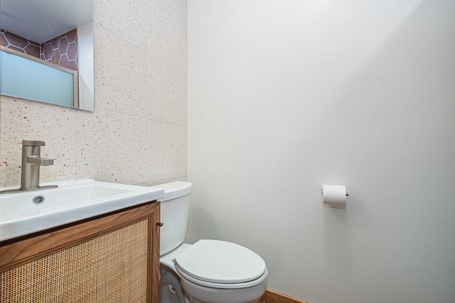 half bathroom with toilet, tile walls, and vanity