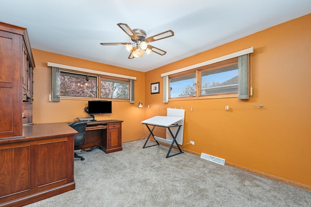 office featuring light colored carpet, a ceiling fan, baseboards, and visible vents