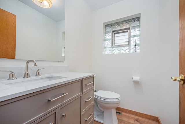 bathroom with vanity, baseboards, toilet, and wood finished floors
