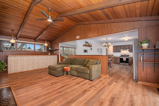 living area featuring lofted ceiling with beams, light wood-style floors, wood walls, ceiling fan with notable chandelier, and wooden ceiling