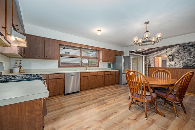 kitchen with light wood-style floors, light countertops, a sink, appliances with stainless steel finishes, and a notable chandelier