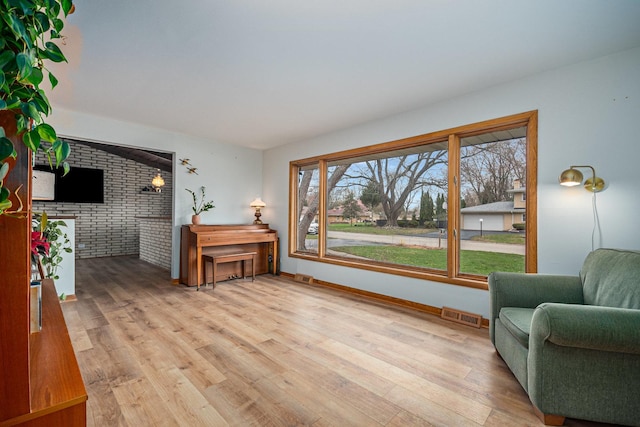 living room featuring visible vents, light wood finished floors, and baseboards