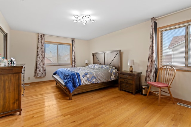 bedroom with light wood-style flooring, visible vents, and multiple windows