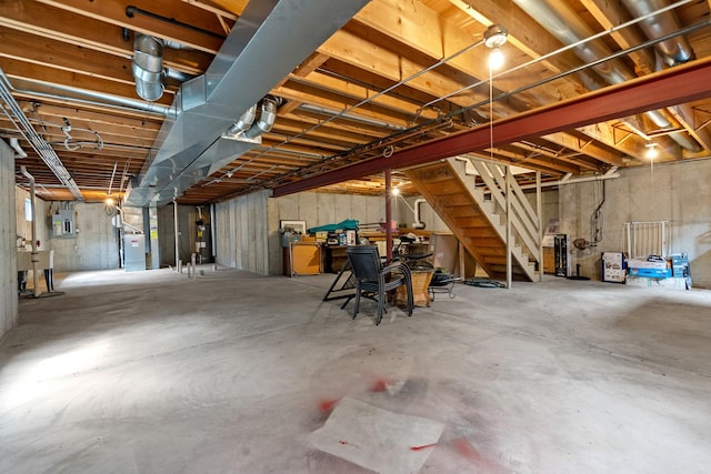 unfinished basement featuring electric panel, water heater, and stairway