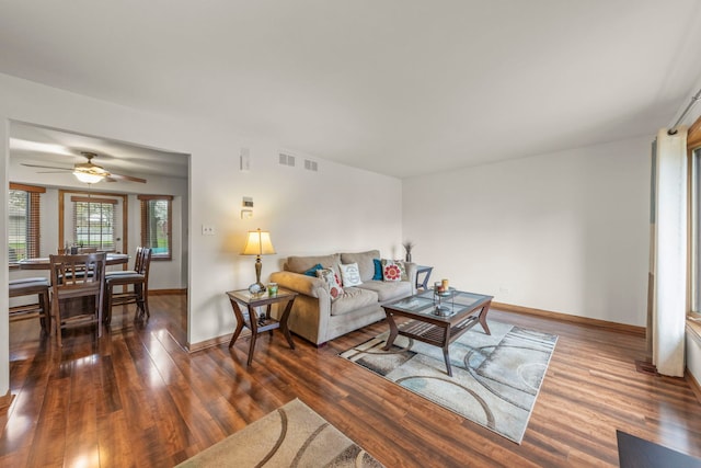 living area featuring a ceiling fan, baseboards, visible vents, and wood finished floors