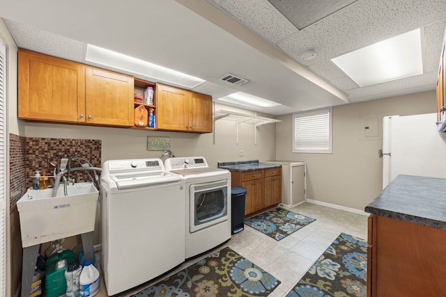 washroom with visible vents, cabinet space, a sink, baseboards, and washer and clothes dryer