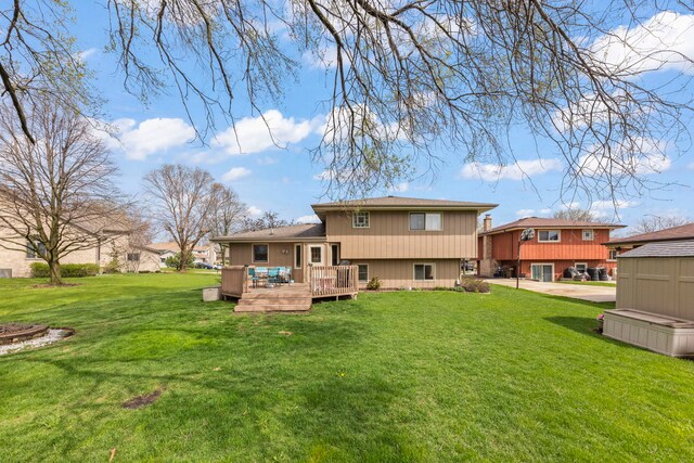 rear view of house featuring a lawn and a deck