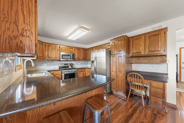 kitchen with visible vents, a peninsula, brown cabinets, a sink, and stainless steel appliances
