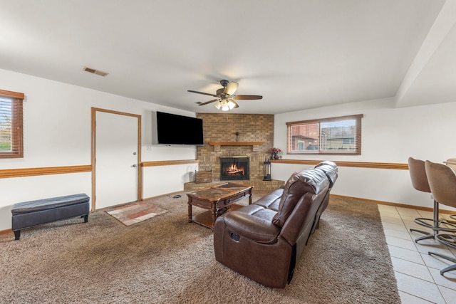 living room with plenty of natural light, a fireplace, a ceiling fan, and visible vents