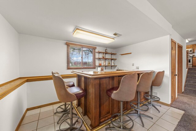 bar with indoor bar, baseboards, and light tile patterned floors