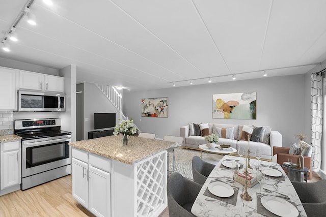 711 W Gordon Ter Unit 103, Chicago, IL 60613 - kitchen with track lighting, appliances with stainless steel finishes, open floor plan, and light wood-type flooring