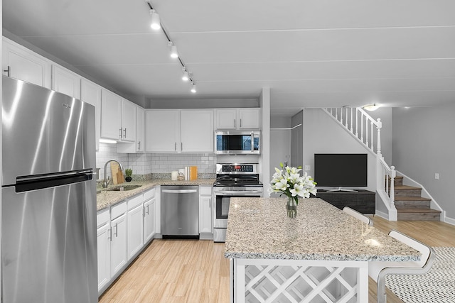 711 W Gordon Ter Unit 103, Chicago, IL 60613 - kitchen featuring a sink, white cabinetry, light wood-type flooring, and appliances with stainless steel finishes