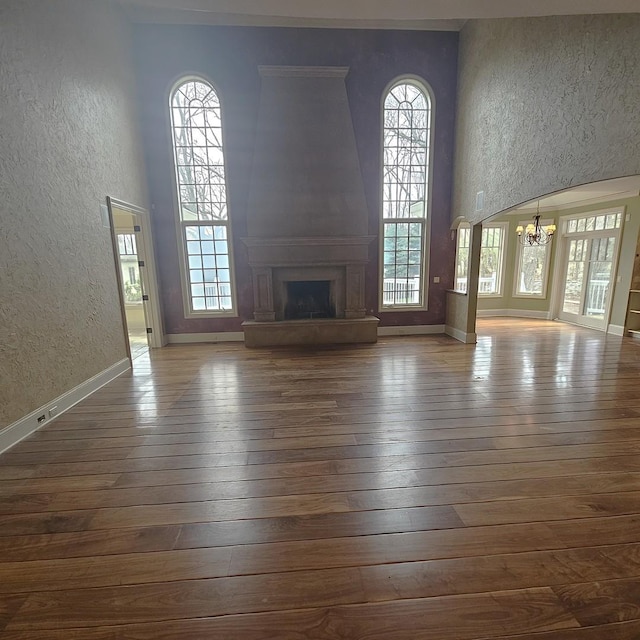 9065 Edinburgh Ct, Lakewood, IL 60014 - unfurnished living room with a large fireplace, baseboards, dark wood-style floors, a chandelier, and a textured wall