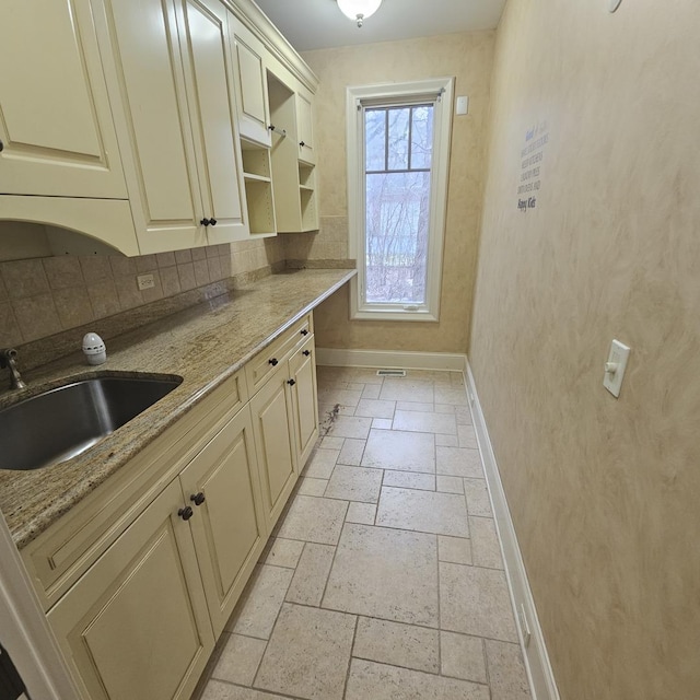 9065 Edinburgh Ct, Lakewood, IL 60014 - kitchen featuring baseboards, stone tile floors, a sink, and cream cabinets