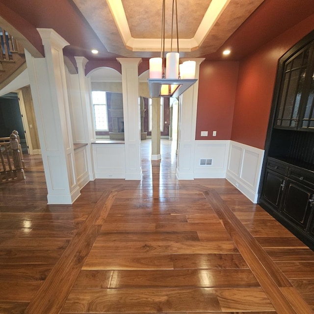 9065 Edinburgh Ct, Lakewood, IL 60014 - unfurnished dining area with a raised ceiling, decorative columns, dark wood-type flooring, and a decorative wall