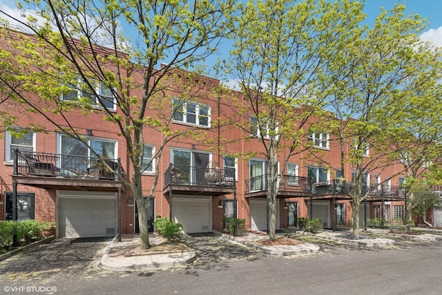 multi unit property featuring an attached garage, driveway, and brick siding