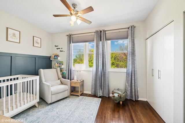 bedroom featuring a crib, ceiling fan, and wood finished floors