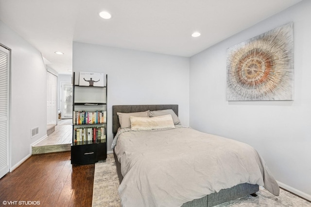 bedroom with baseboards, recessed lighting, wood finished floors, and visible vents
