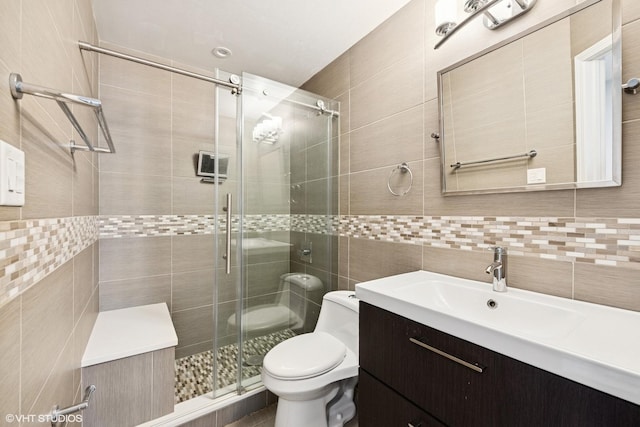 bathroom featuring vanity, toilet, tile walls, tasteful backsplash, and a stall shower