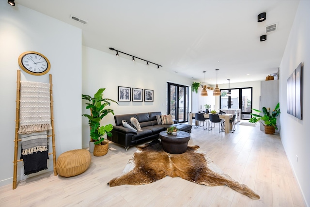 living room with baseboards, visible vents, rail lighting, and light wood-style flooring