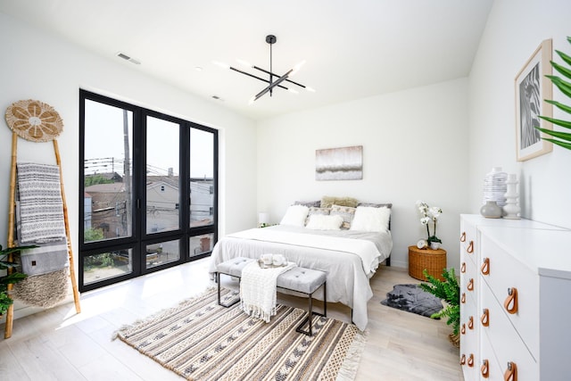 bedroom featuring light wood finished floors, an inviting chandelier, and visible vents