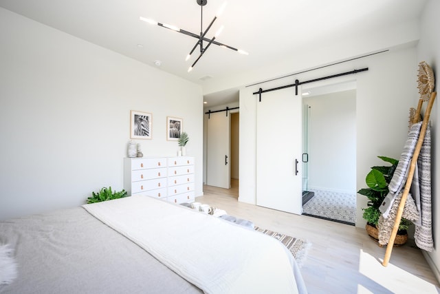 bedroom with light wood finished floors, a chandelier, and a barn door