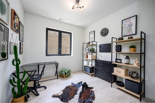 office space featuring baseboards, visible vents, wood finished floors, and a notable chandelier